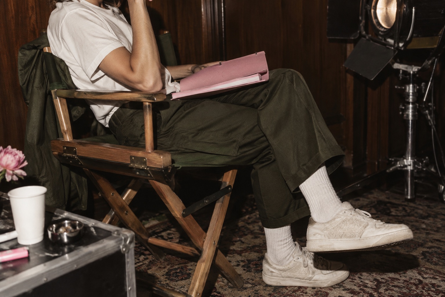 A performer with a pink script binder in an olive director chair